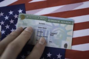 Permanent Resident Green card of United states of America on flag of USA. Concept for Green Card to Citizenship: Navigating the Naturalization Process